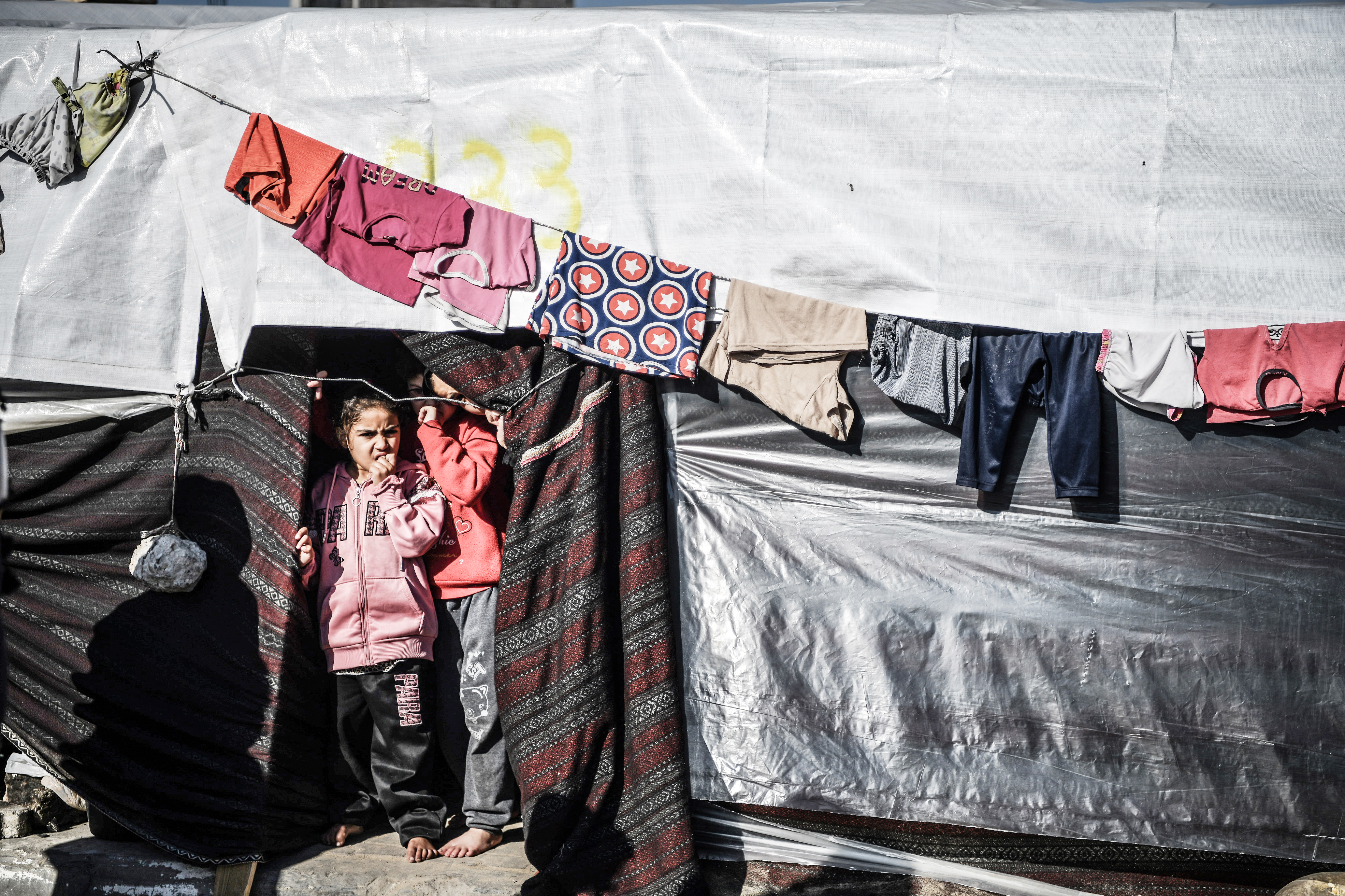 Displaced Palestinian children stand in a tent in Rafah, southern Gaza