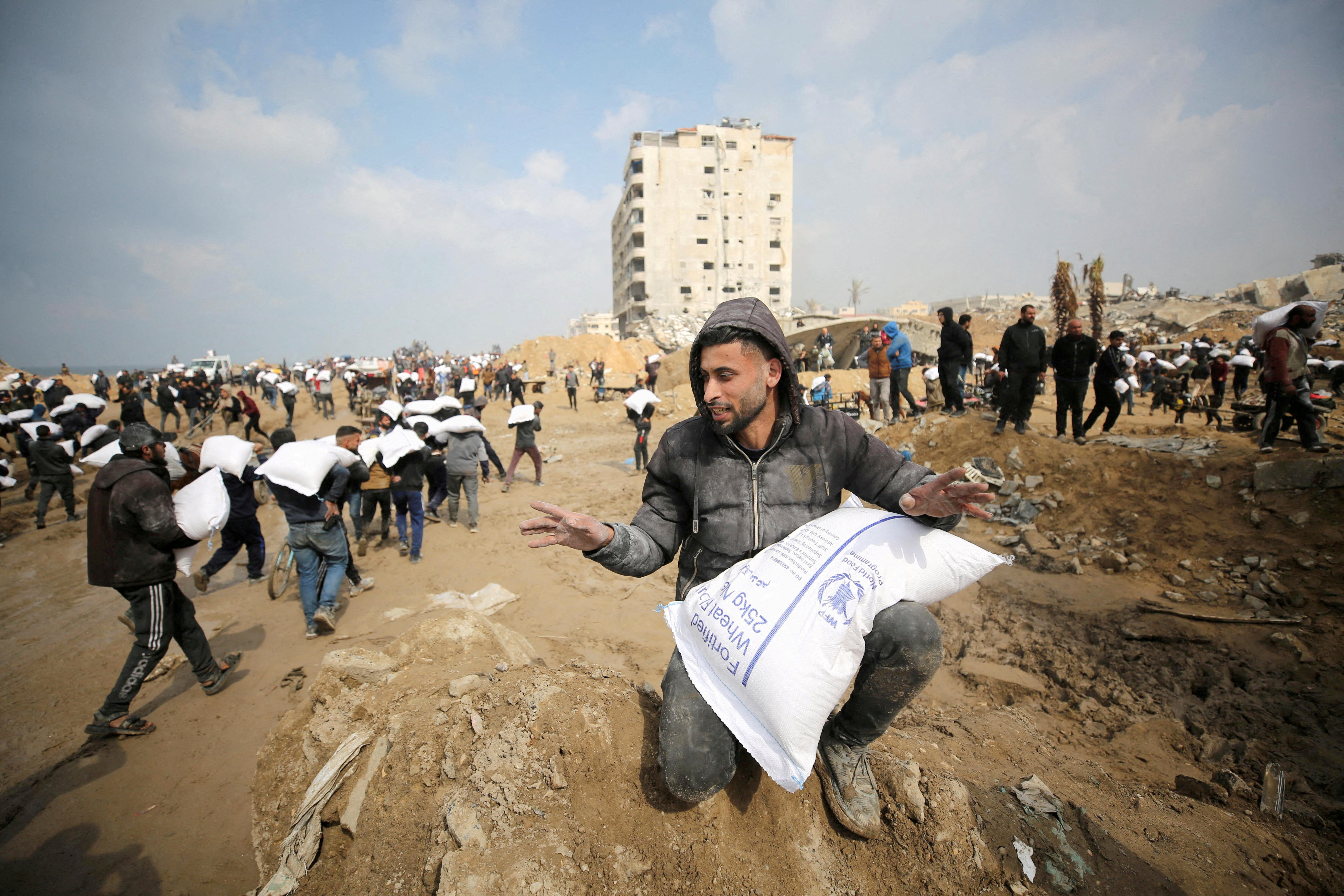 Palestinians carry bags of flour they grabbed from an aid truck near an Israeli checkpoint, as Gaza residents face crisis levels of hunger