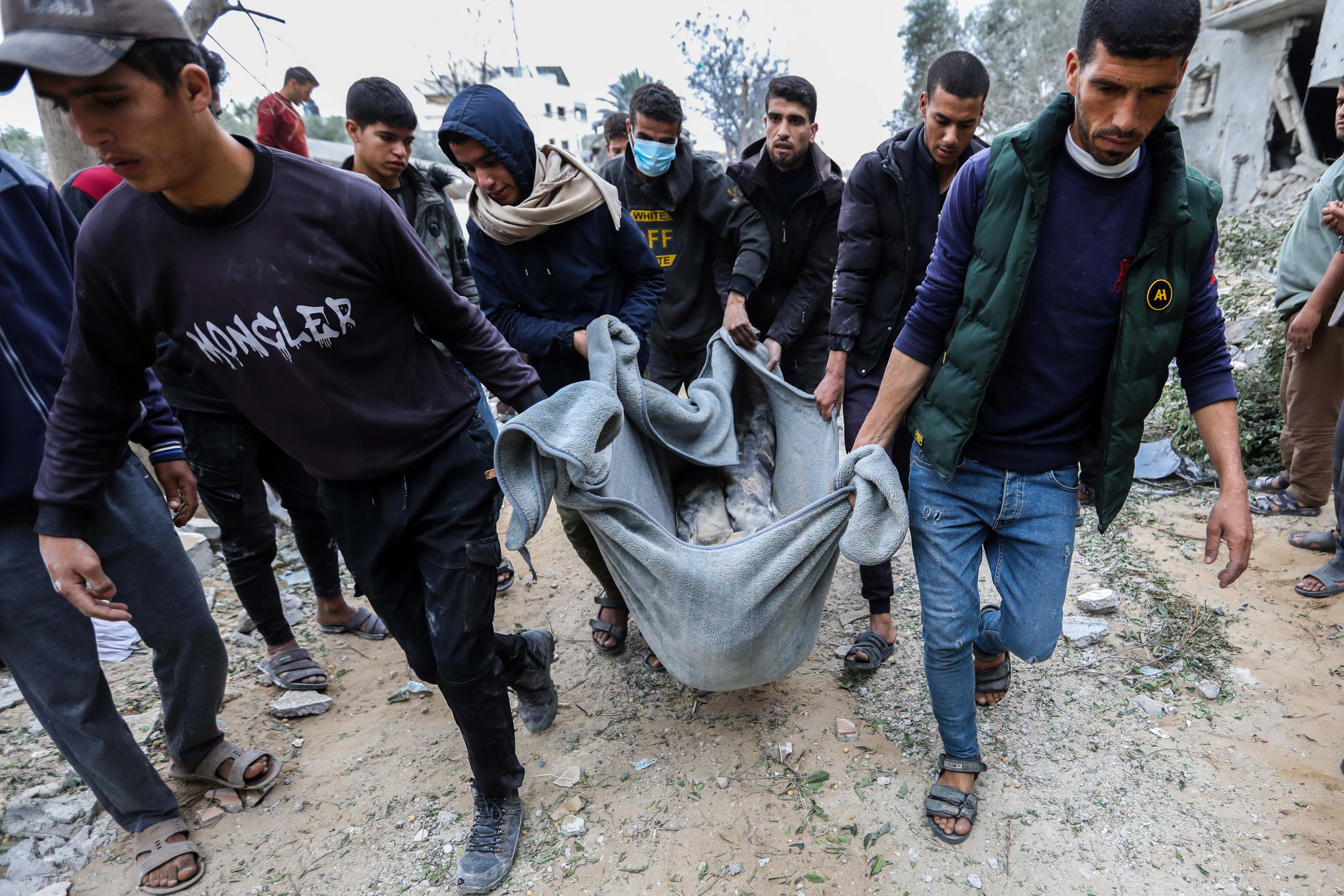People recover the body of a child from a destroyed building following Israeli air strikes