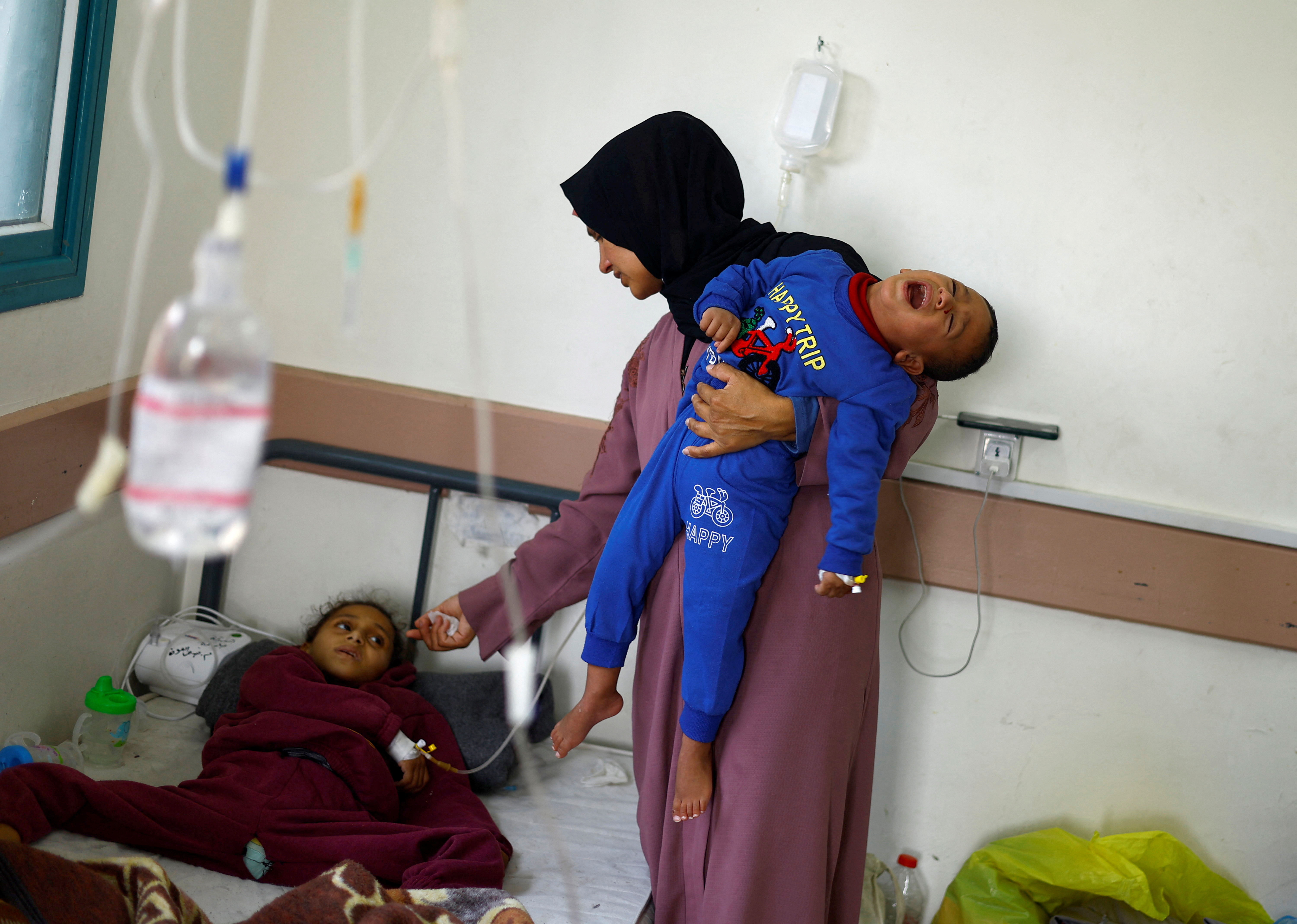 A Palestinian woman Kholod Al- Masri looks after her children Mohammed and Maram, who suffer from malnutrition, at al-Awda health centre, amid widespread hunger, as the conflict between Israel and the Palestinian Islamist group Hamas continues, in Rafah